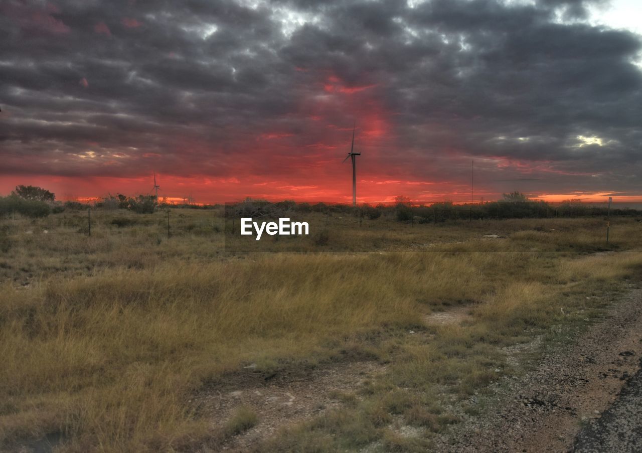 ELECTRICITY PYLON ON FIELD AGAINST SKY AT SUNSET