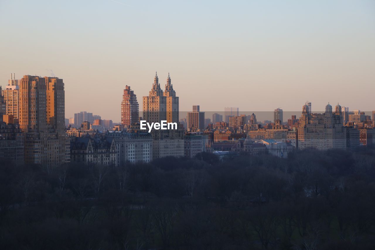 Buildings in city against clear sky during sunset