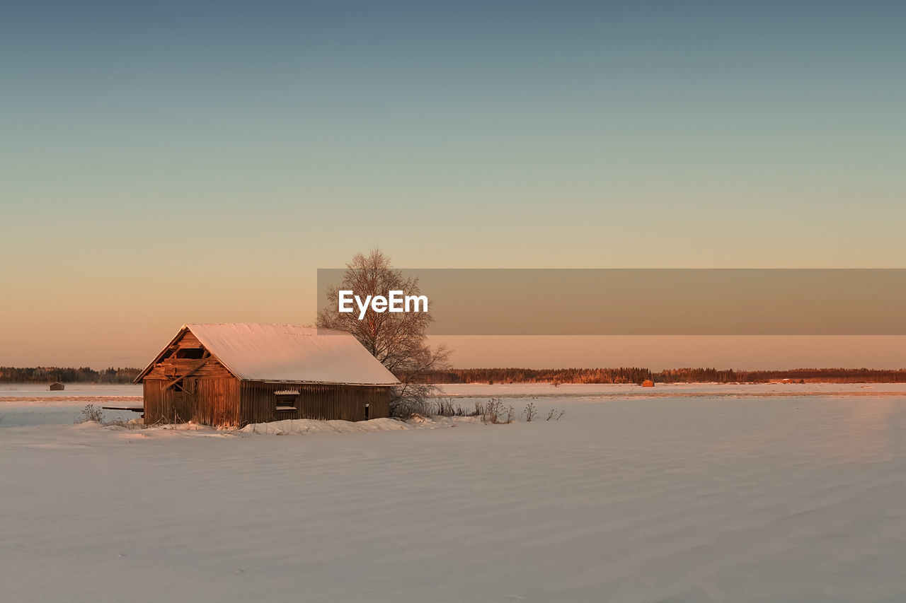 The winter sun rises and colours the snow covered landscape beautifully at the rural finland. 