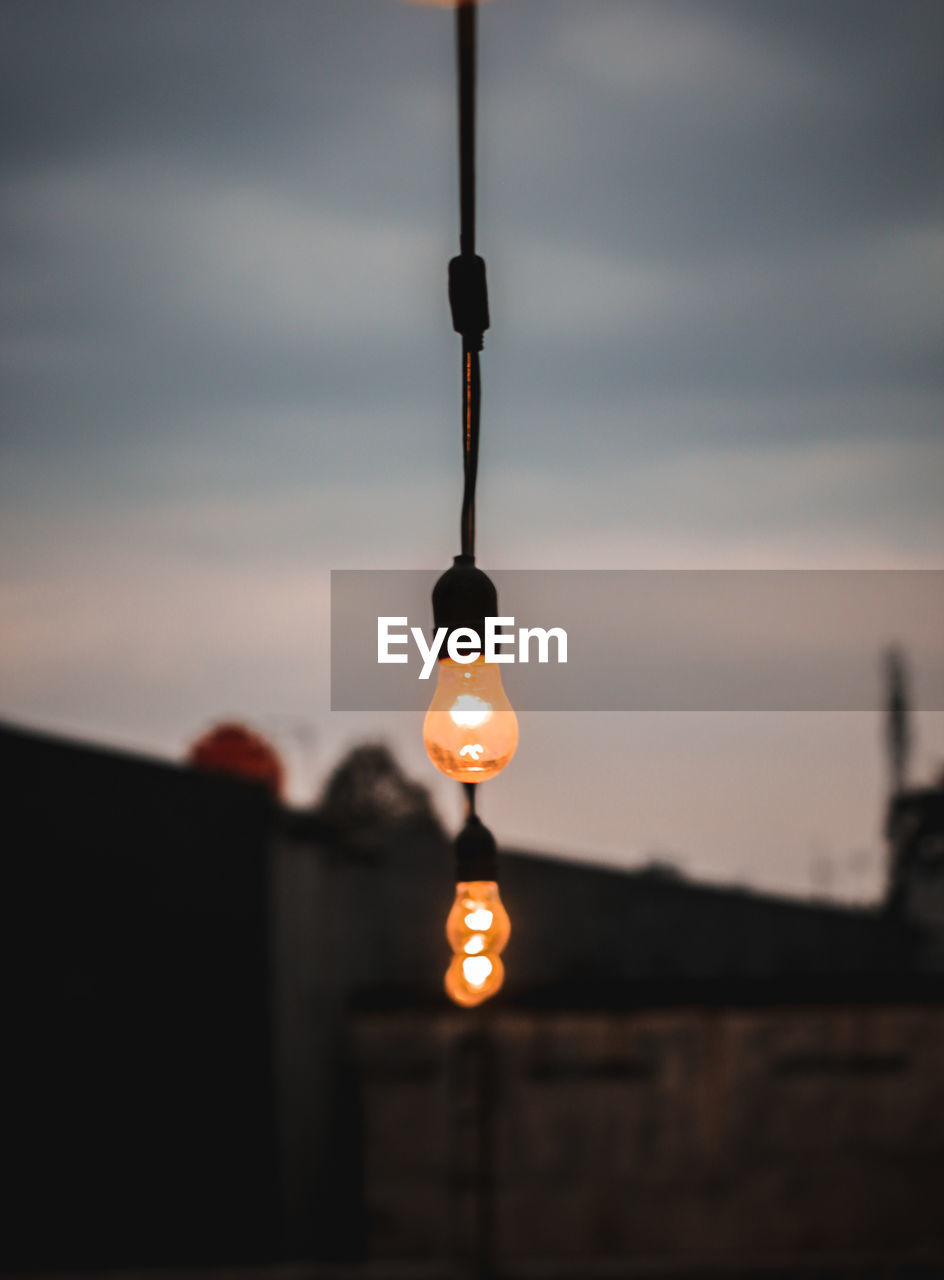 LOW ANGLE VIEW OF ILLUMINATED LIGHT BULBS AGAINST SKY