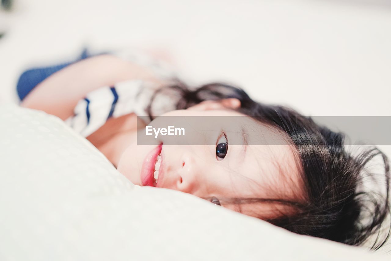 Portrait of cute girl lying on bed at home