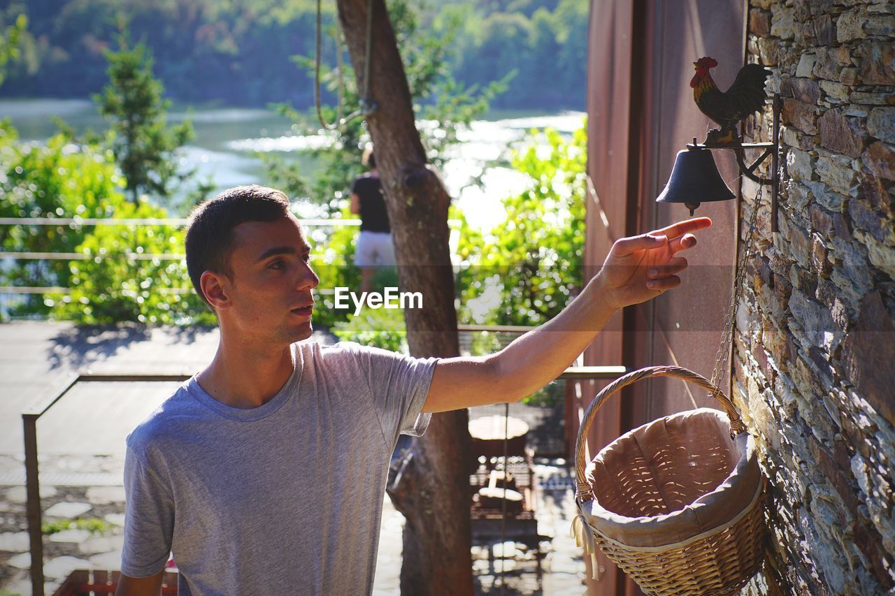 Young man ringing bell while standing by door