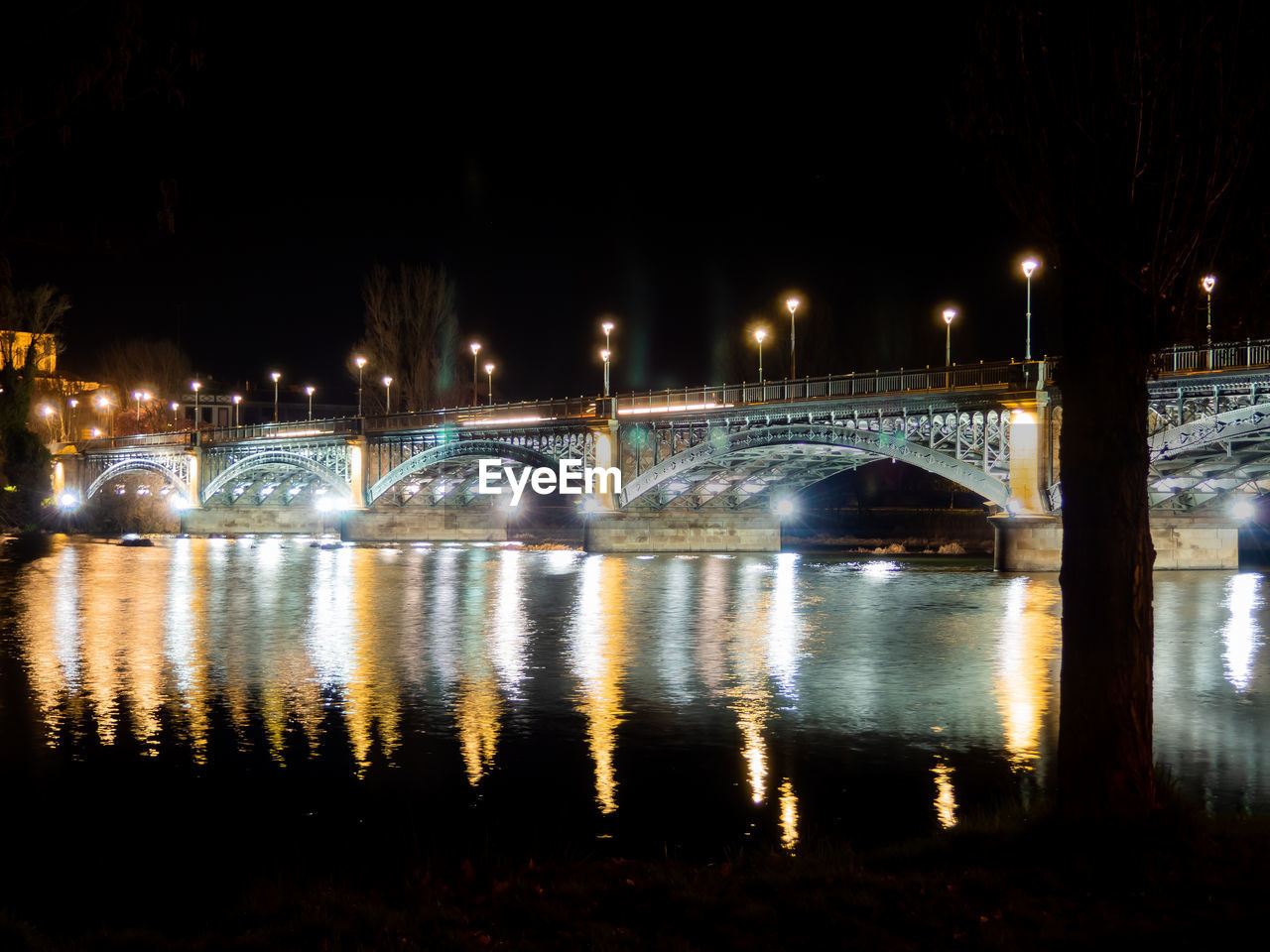 ILLUMINATED BRIDGE OVER RIVER IN CITY