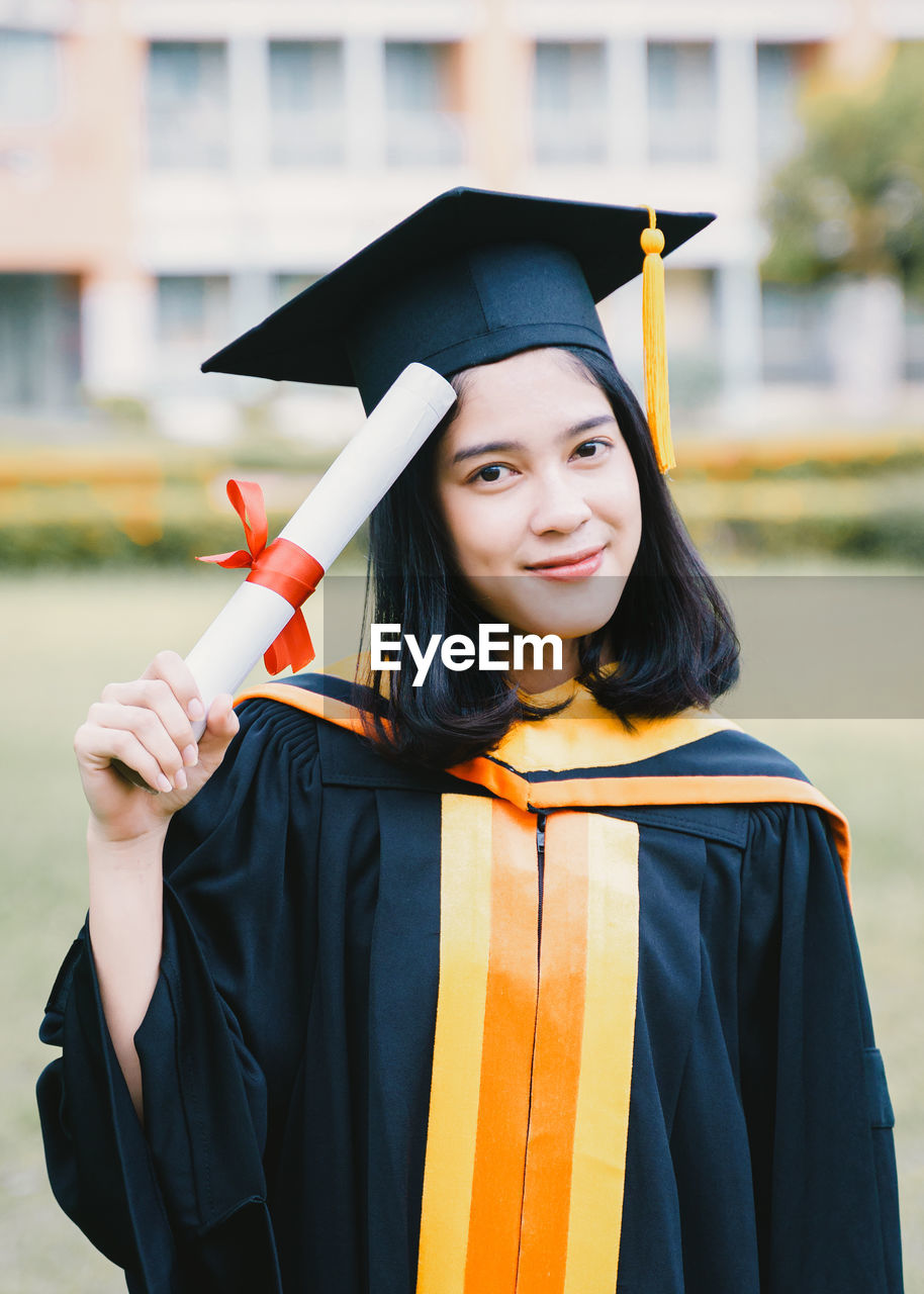 PORTRAIT OF SMILING YOUNG WOMAN STANDING AGAINST YELLOW