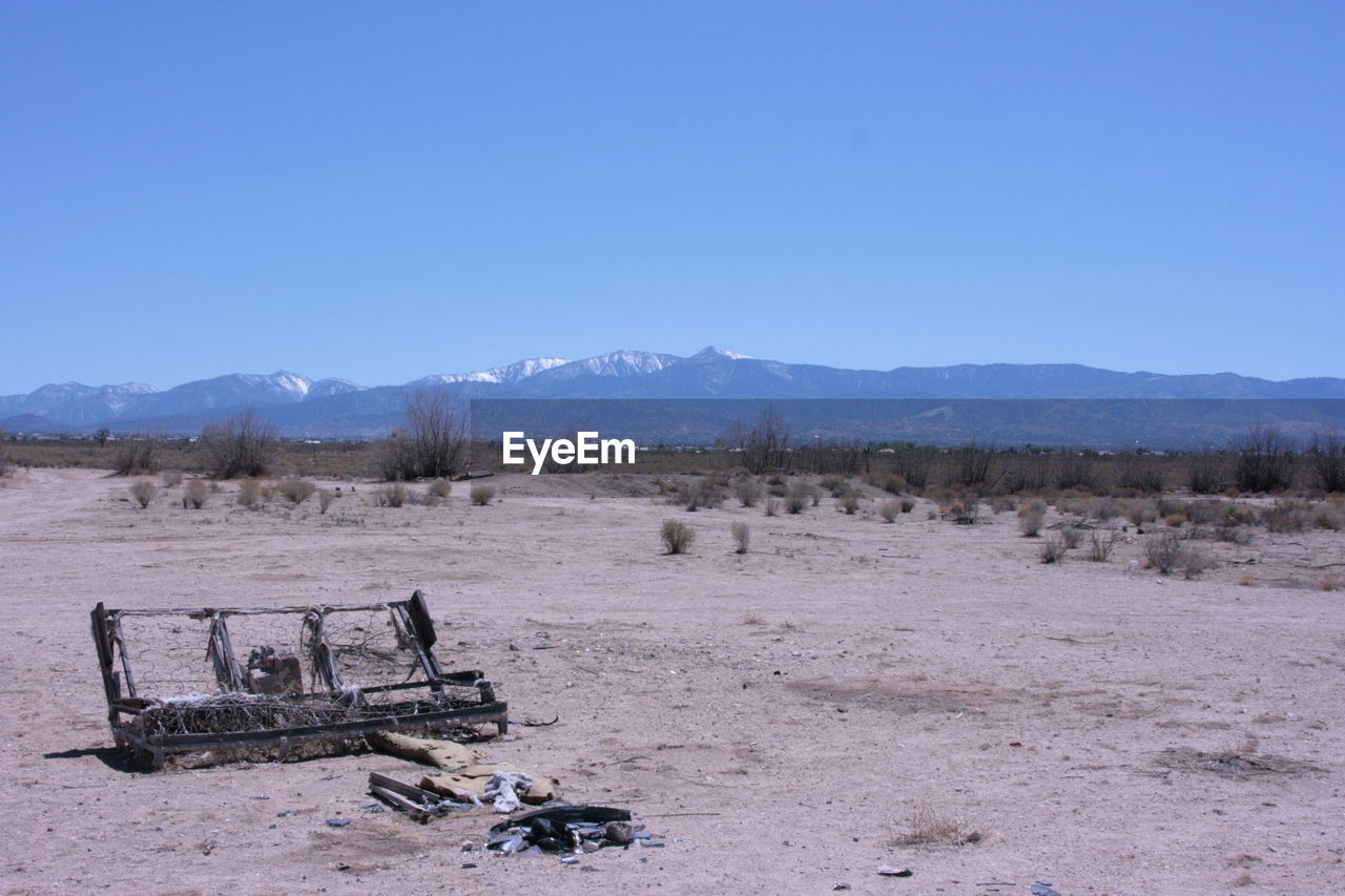 Abandoned bed frame on barren landscape 