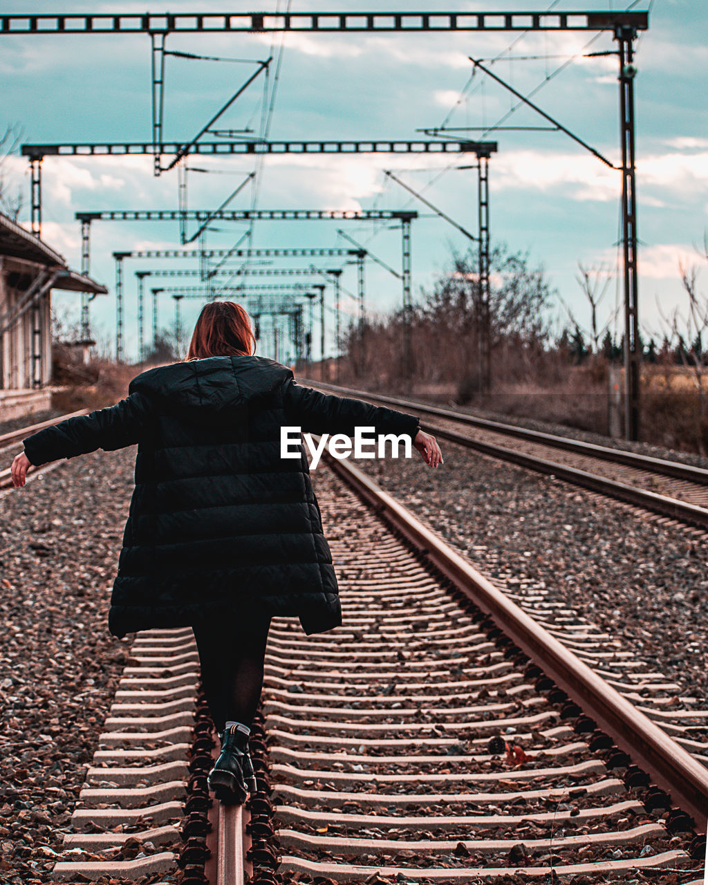 Rear view of woman standing on railroad track