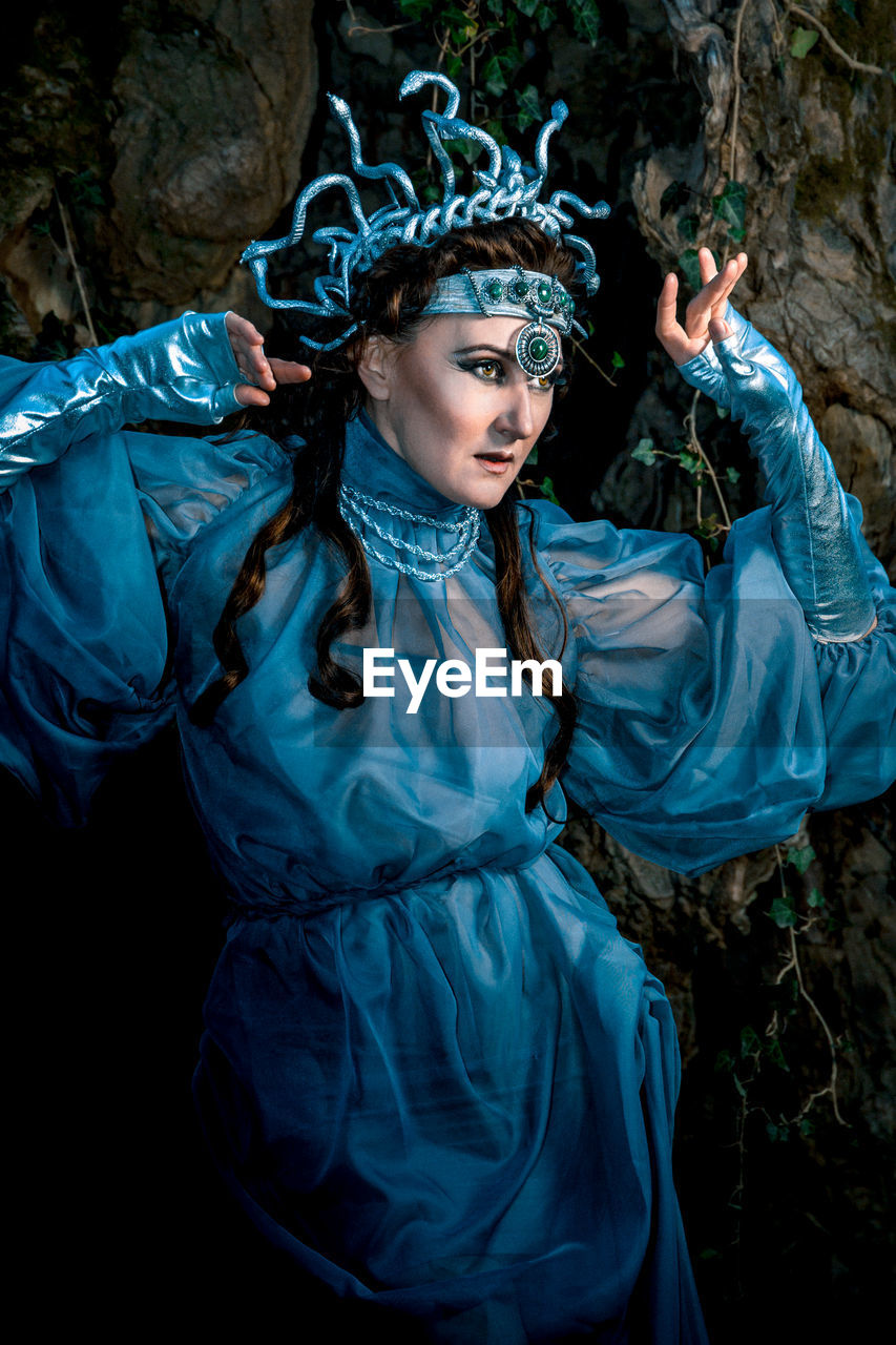 A gloomy portrait of a woman in makeup and a night witch costume on a dark background