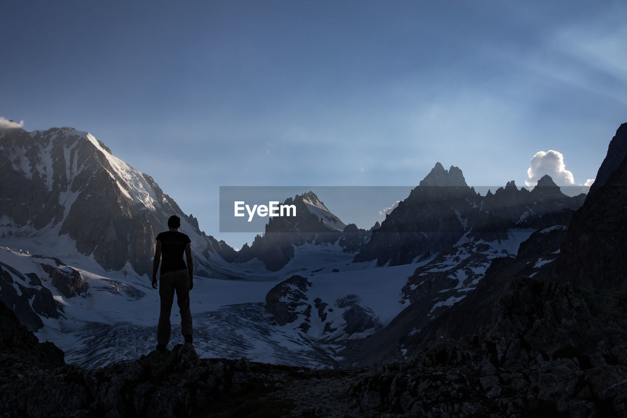 Rear view of silhouette woman standing against snowcapped mountain