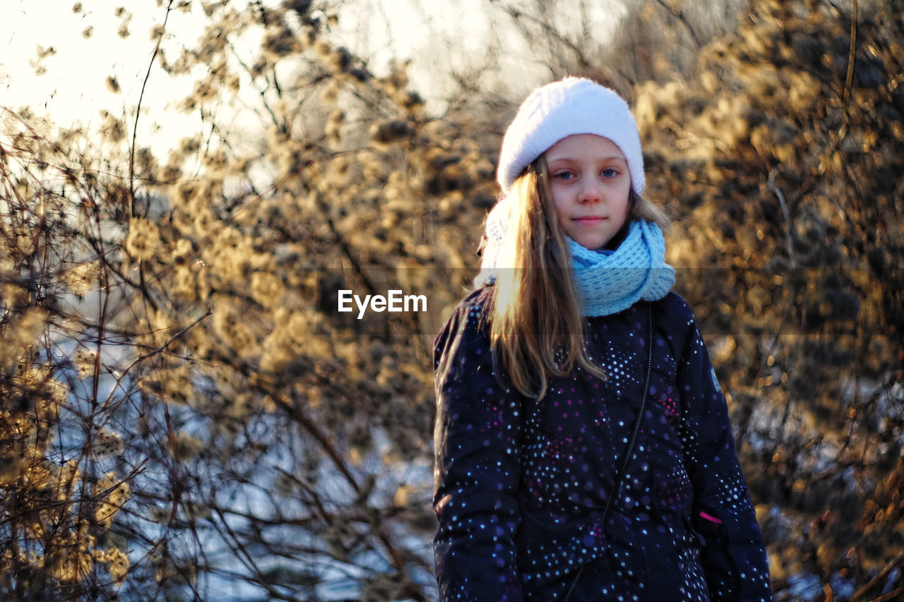Portrait of girl against dried plants during winter