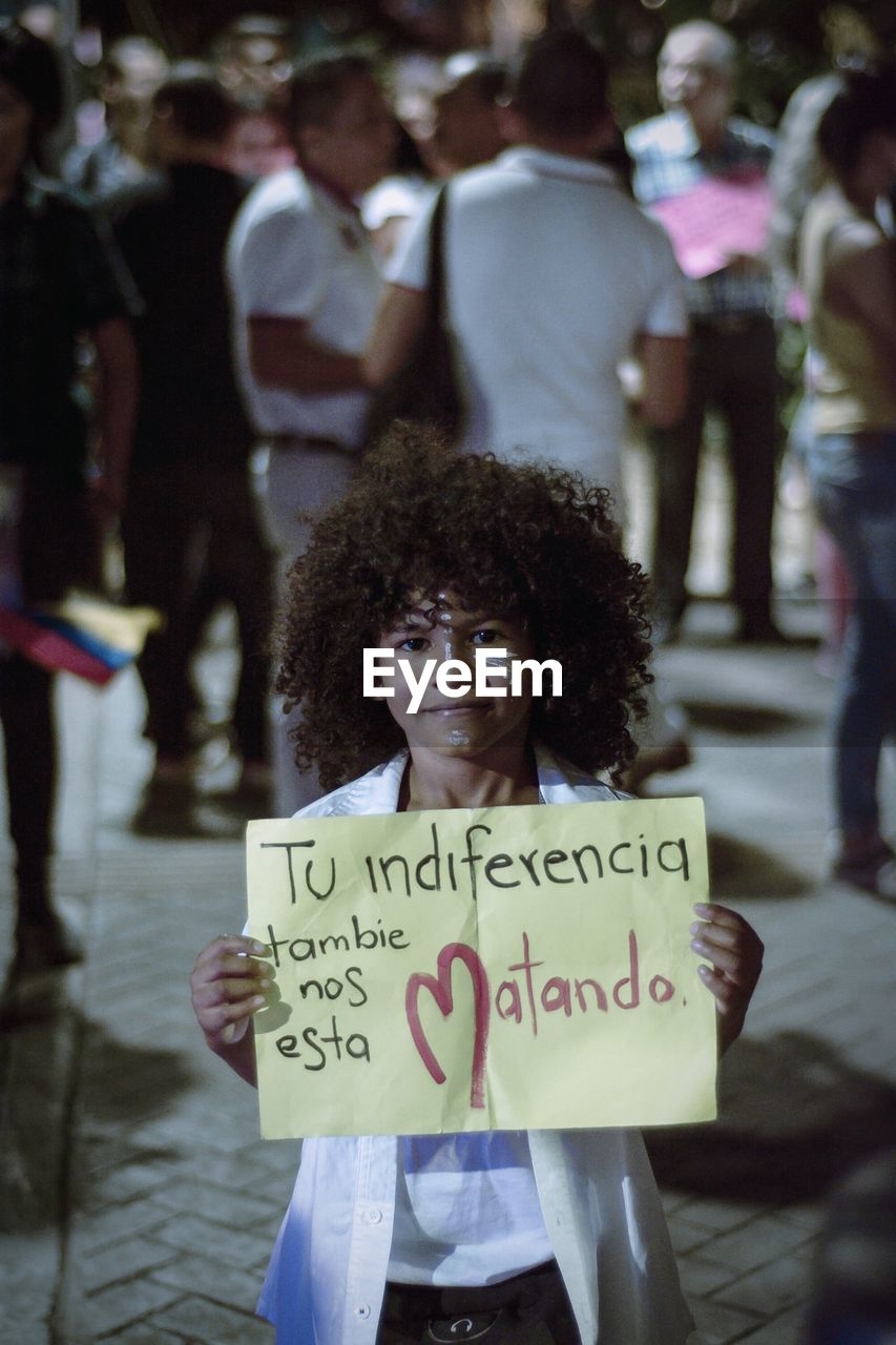 PORTRAIT OF WOMAN WITH TEXT STANDING ON A SIGN