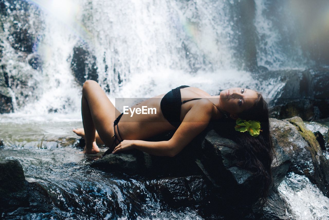 Woman lying in front of waterfall