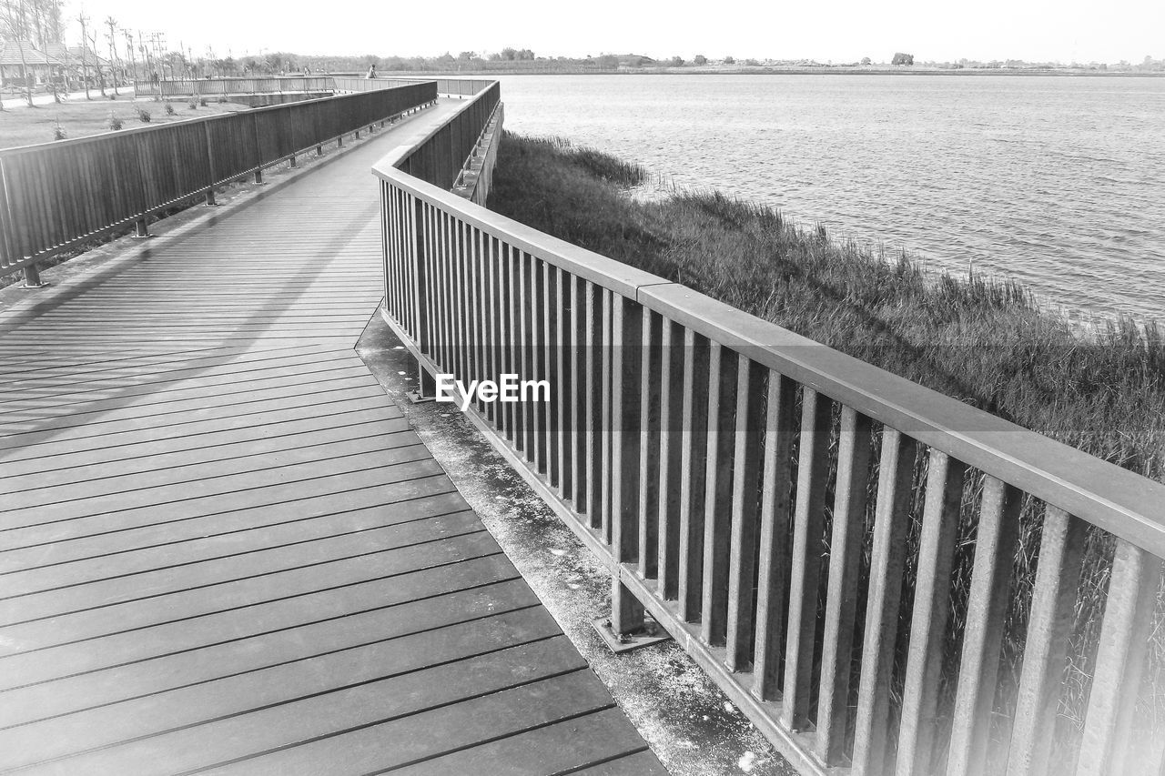 water, nature, black and white, railing, walkway, architecture, sky, day, the way forward, built structure, no people, monochrome photography, footpath, land, bridge, tranquility, scenics - nature, sea, tranquil scene, outdoors, monochrome, plant, beauty in nature, boardwalk, wood, beach, diminishing perspective, landscape, environment, transportation, sunlight, non-urban scene, line, horizon