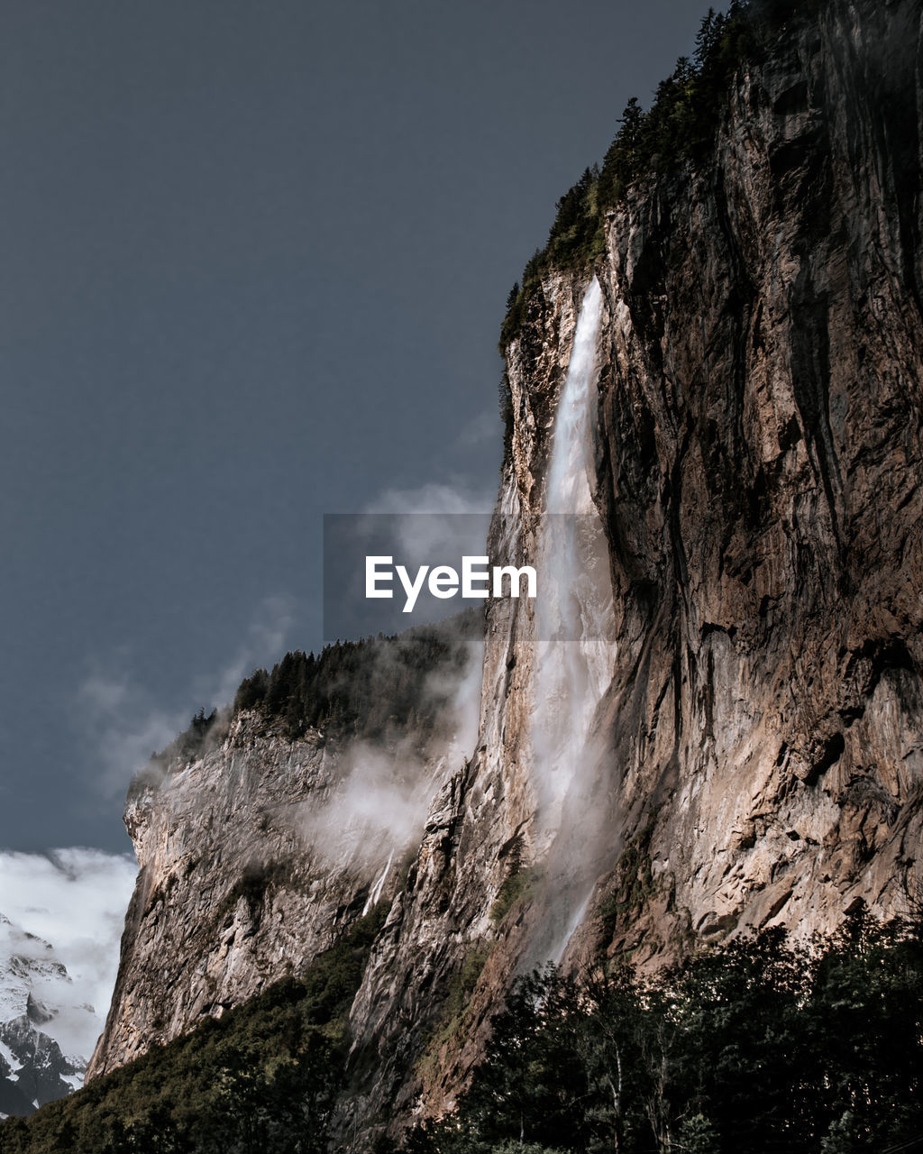 Low angle view of rock formation and waterfall against sky