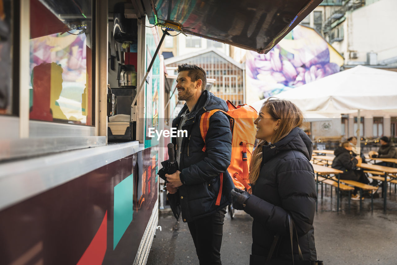 Happy couple standing by counter at food truck