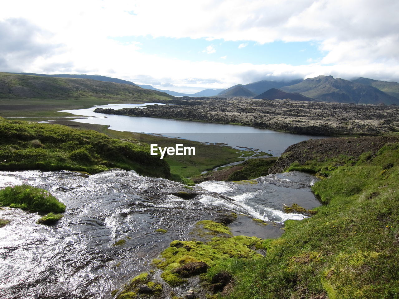 Scenic view of river and mountains against cloudy sky