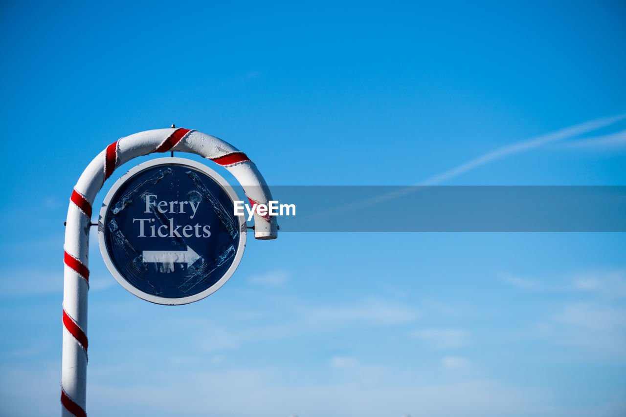 Low angle view of signboard against clear blue sky