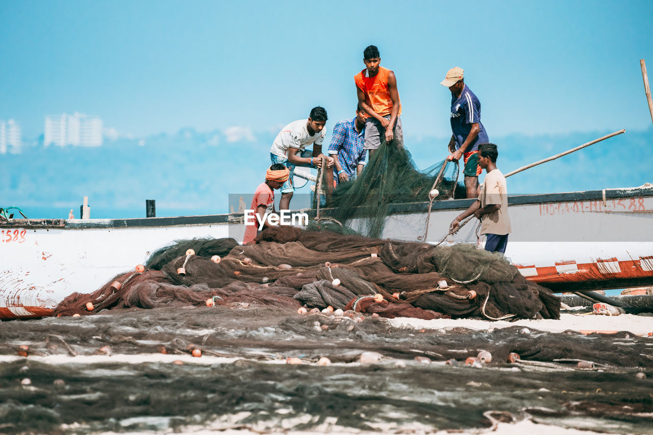 PEOPLE WORKING IN SEA AGAINST SKY