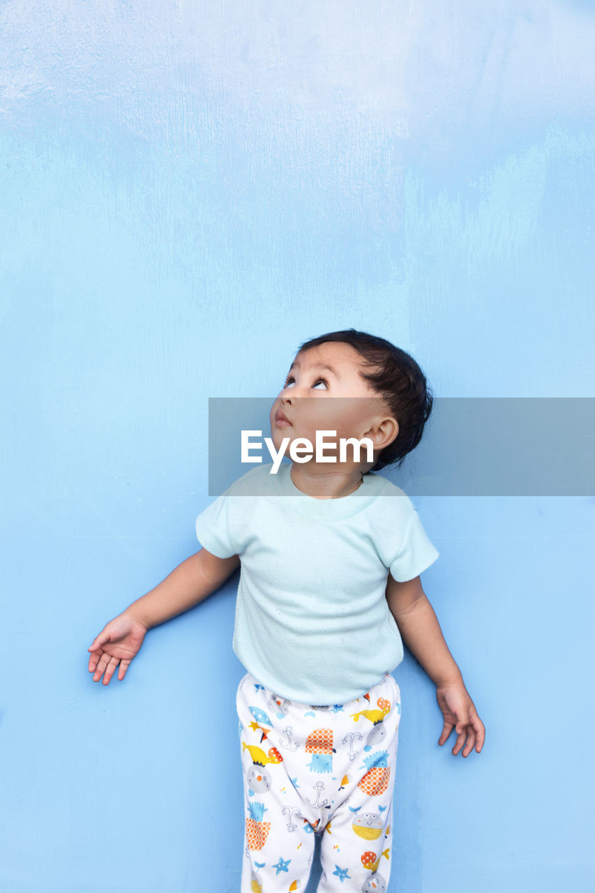 Baby girl standing against blue wall