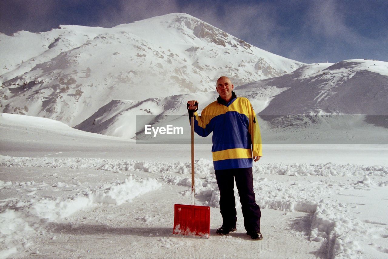 Portrait of man with shovel on snow covered land