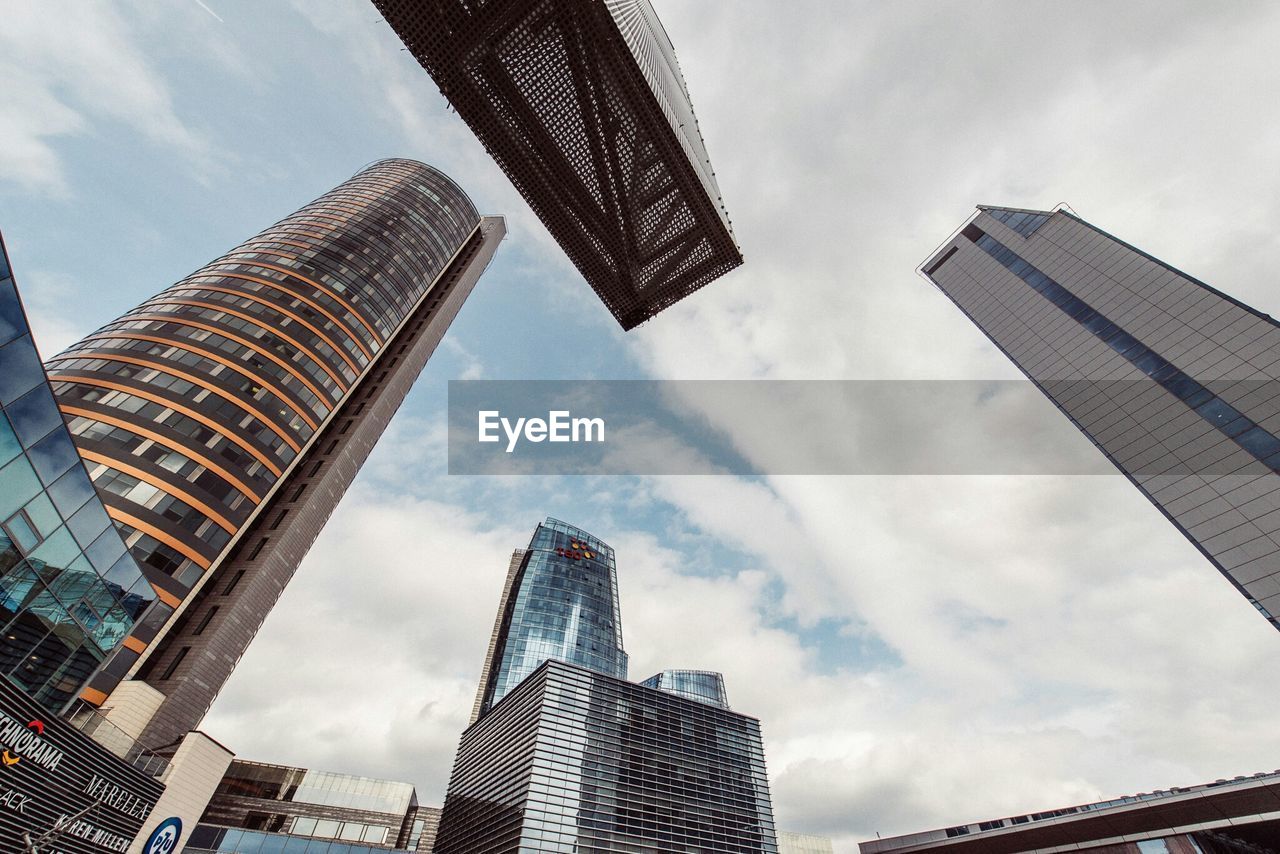 Low angle view of skyscrapers against cloudy sky