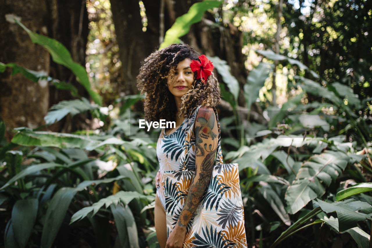 Young woman standing against plants in forest