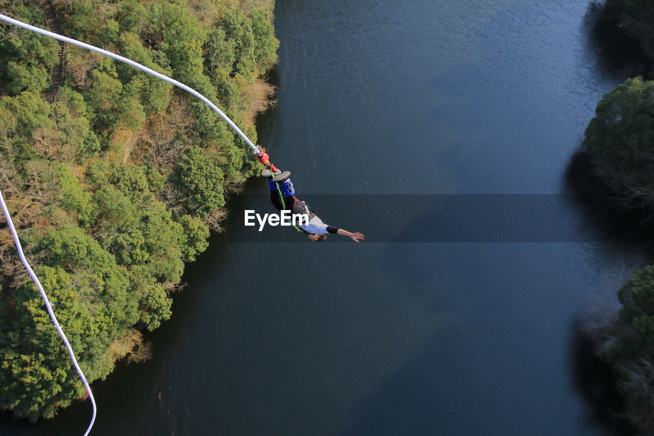 High angle view of man bungee jumping over river