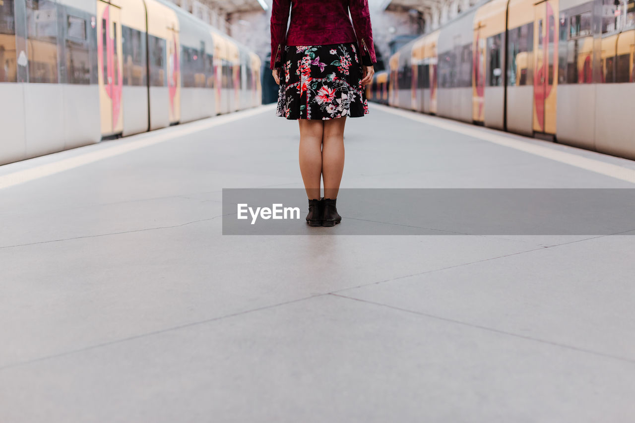 Low section of woman standing on railroad station platform