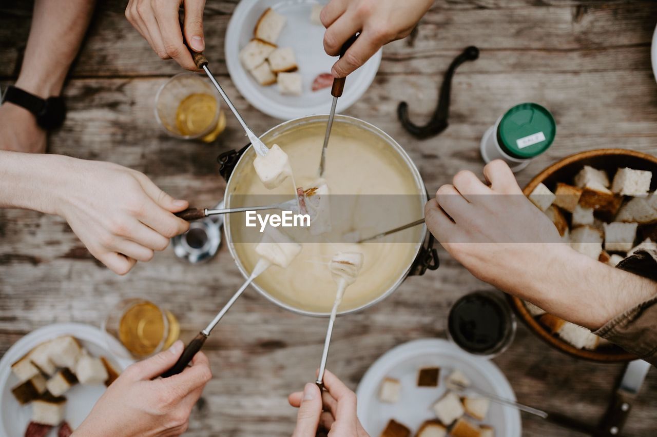 Cropped hands of friends holding breads over dip