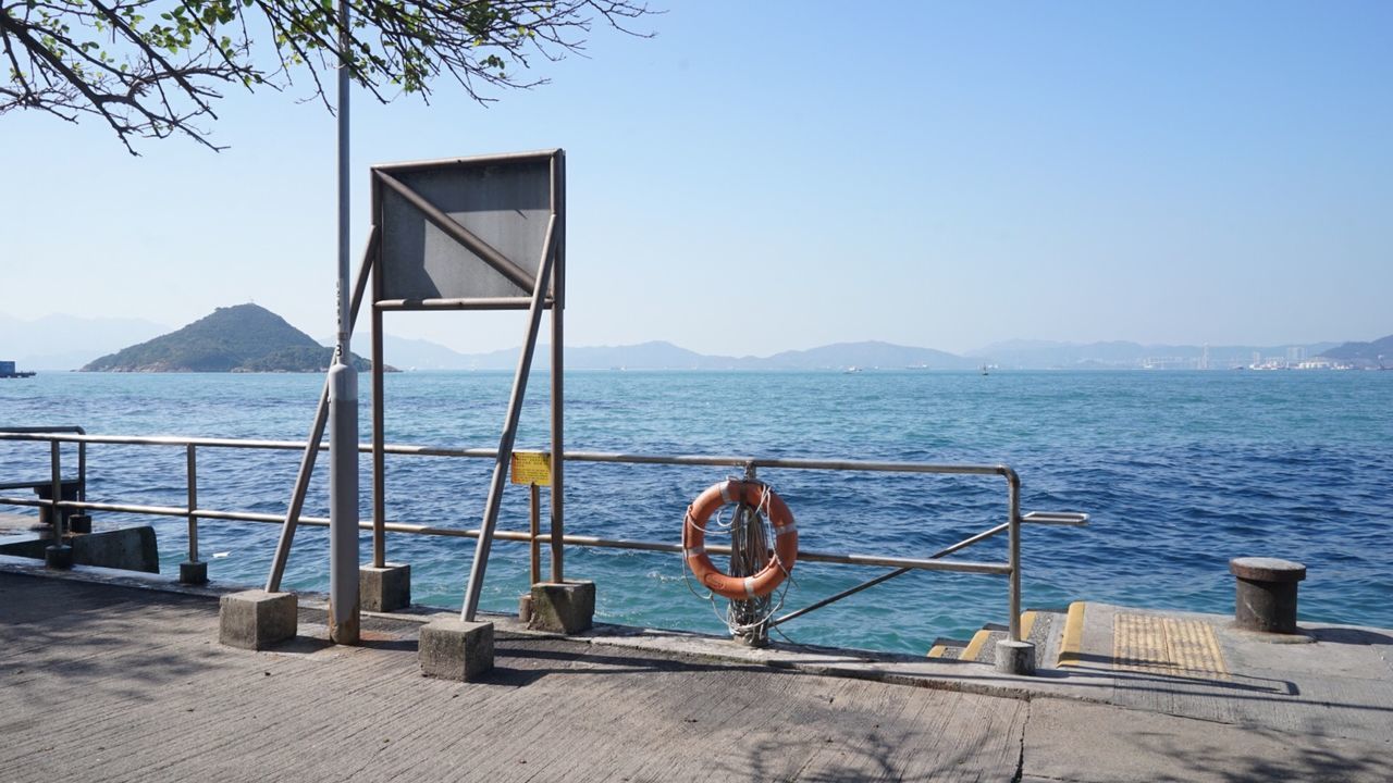 Railing by sea against clear sky