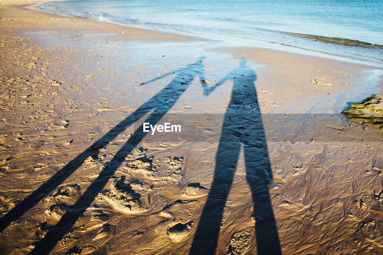 Shadow of couple standing on sand at beach