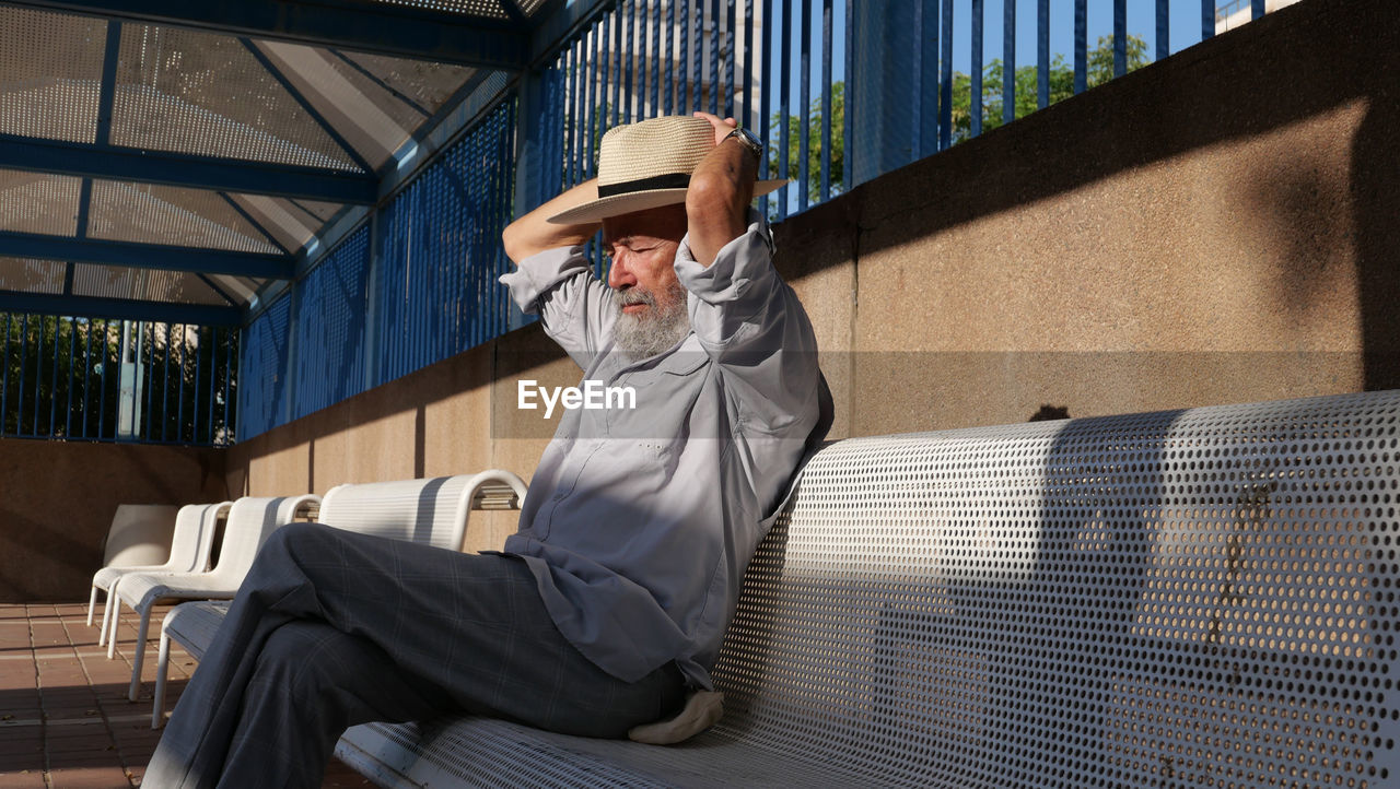 Senior man sitting on bench in town