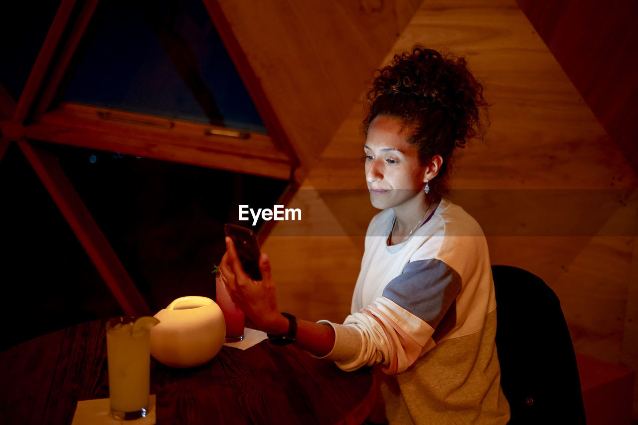 Woman using a mobile phone while relaxing in a dome tent.