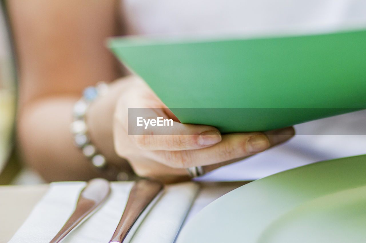 Low section of woman holding paper