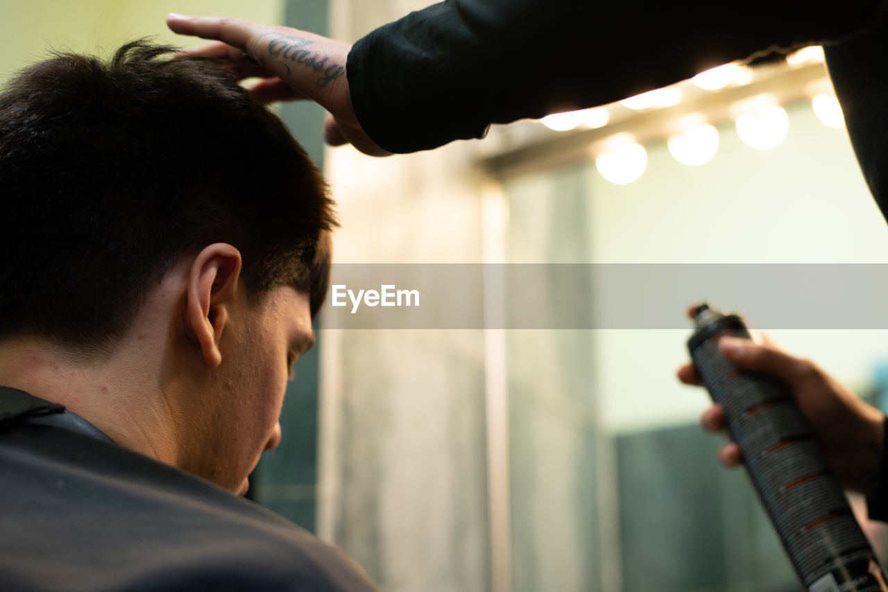 Barber adjusting hair of man at salon