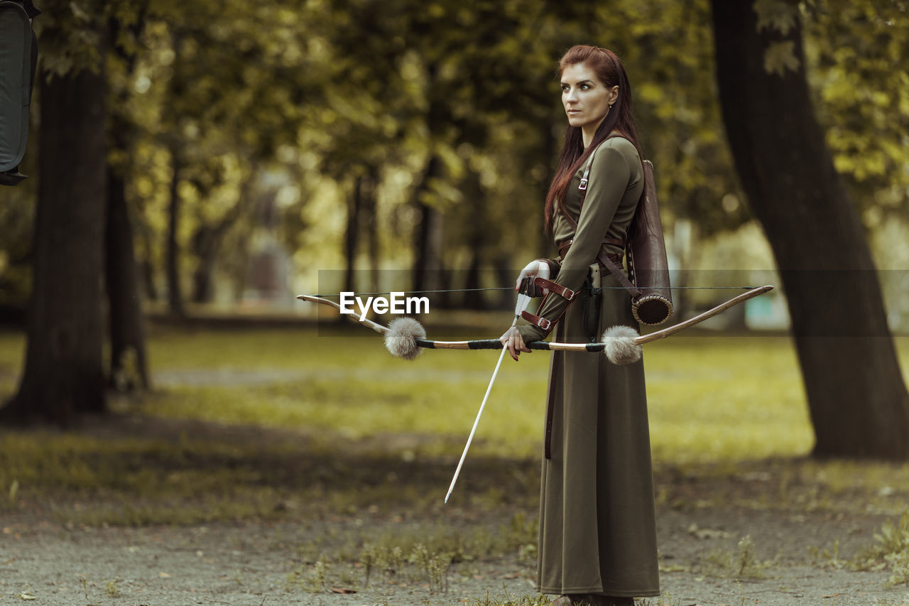 Archer holding bow and arrow while standing outdoors