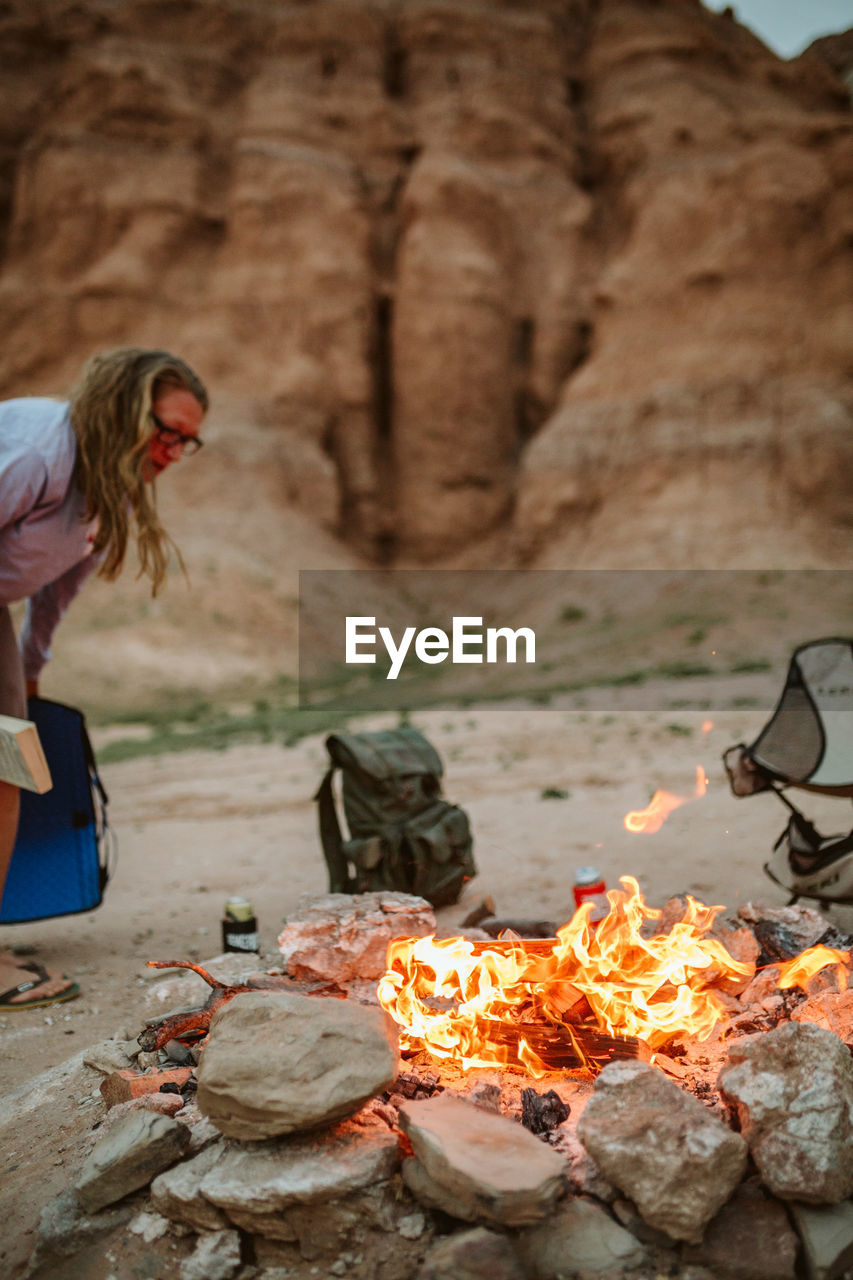 Camper sets up her chair to read next to fire in utah desert