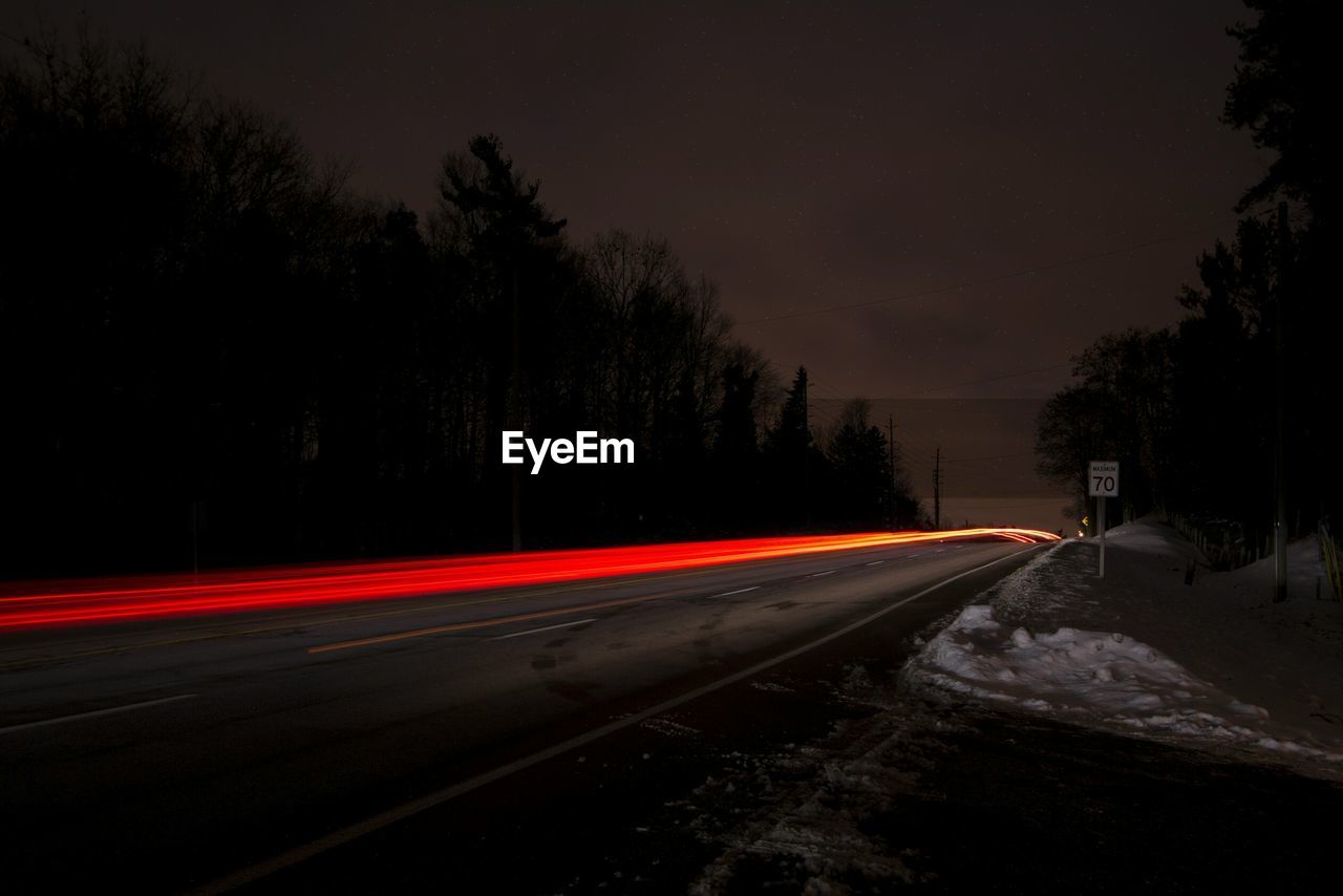 LIGHT TRAILS ON ROAD AT NIGHT DURING WINTER