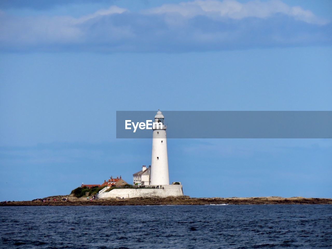 Lighthouse by sea against sky