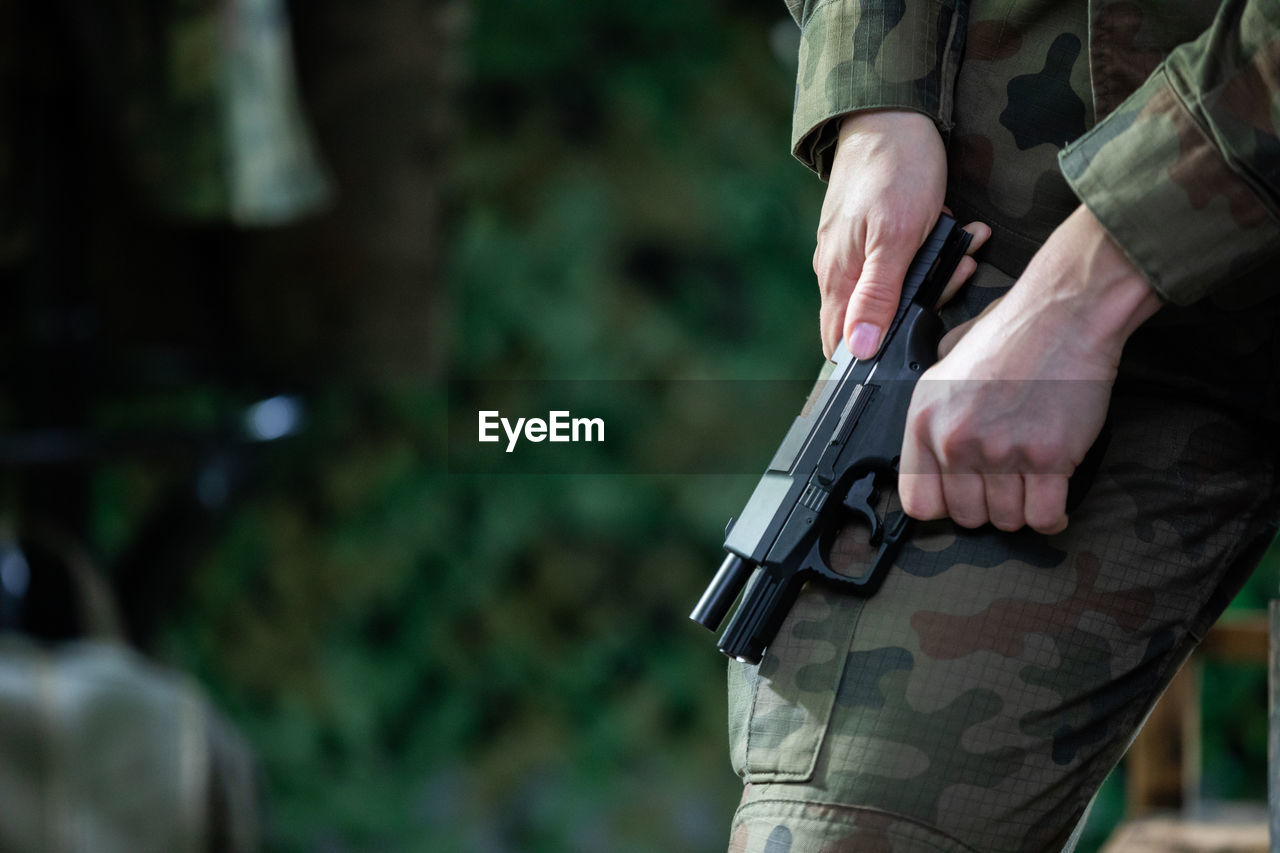 A lady soldier reloads her pistol to keep it charged during an action.