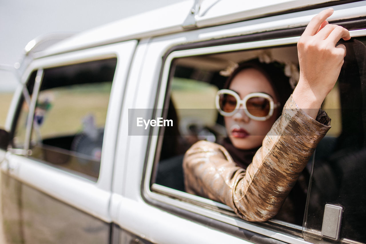 PORTRAIT OF WOMAN IN CAR MIRROR