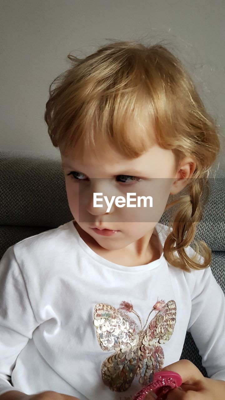 Close-up of girl looking away while sitting on sofa