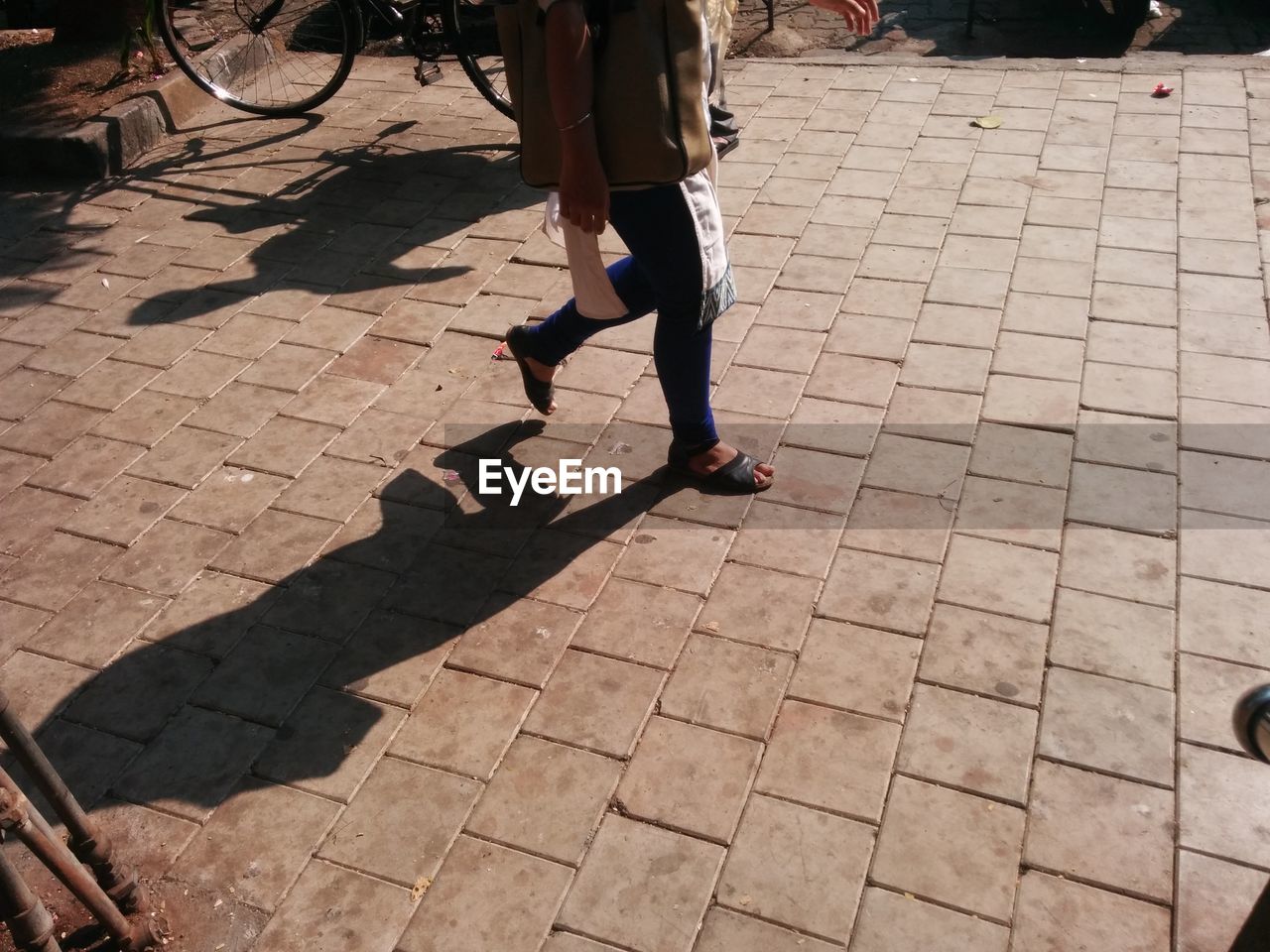 Low section of woman walking on cobblestone street