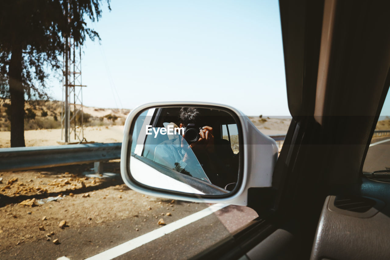 Point of view, perspective, reflection of car on side-view mirror, road trip