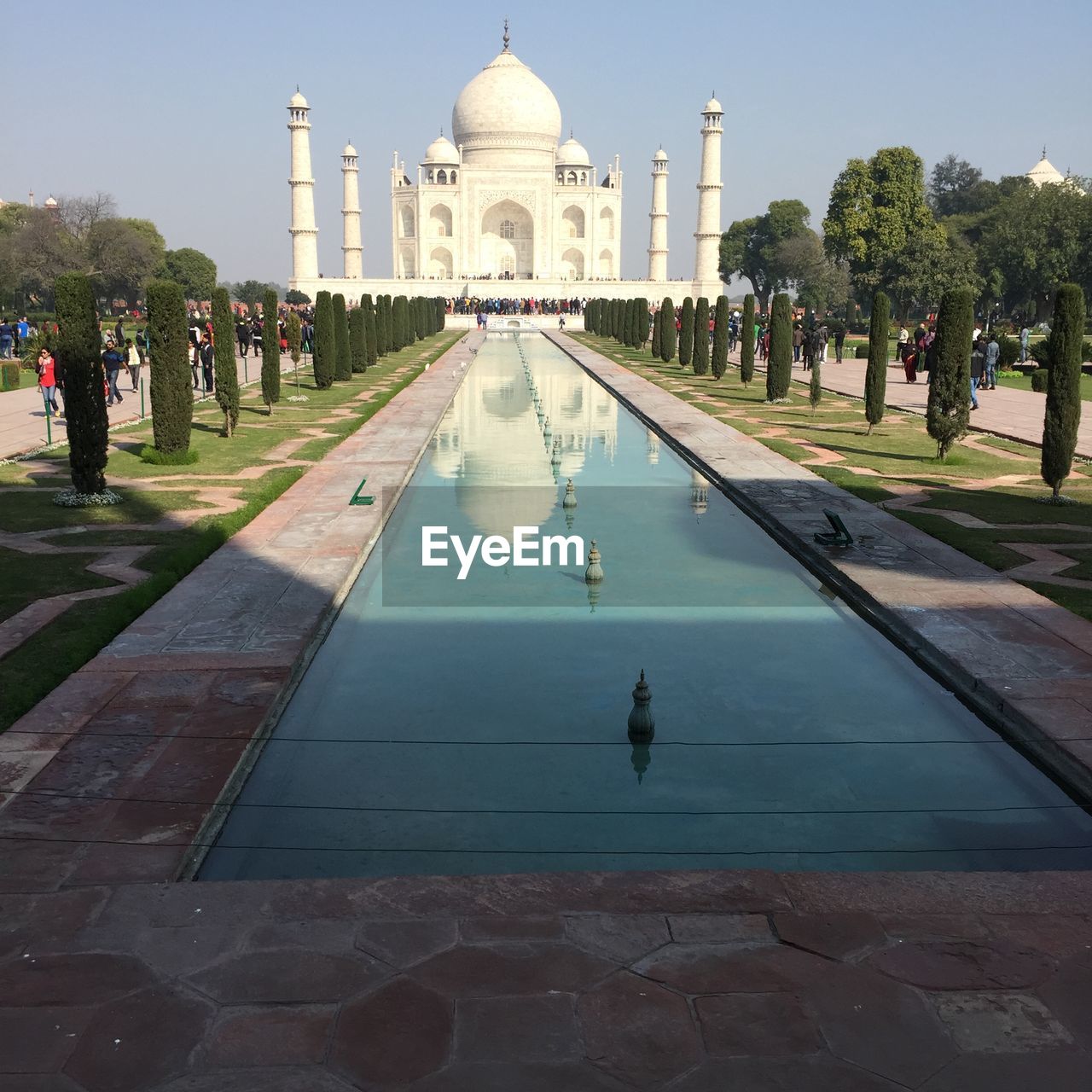 Pond leading towards taj mahal against sky