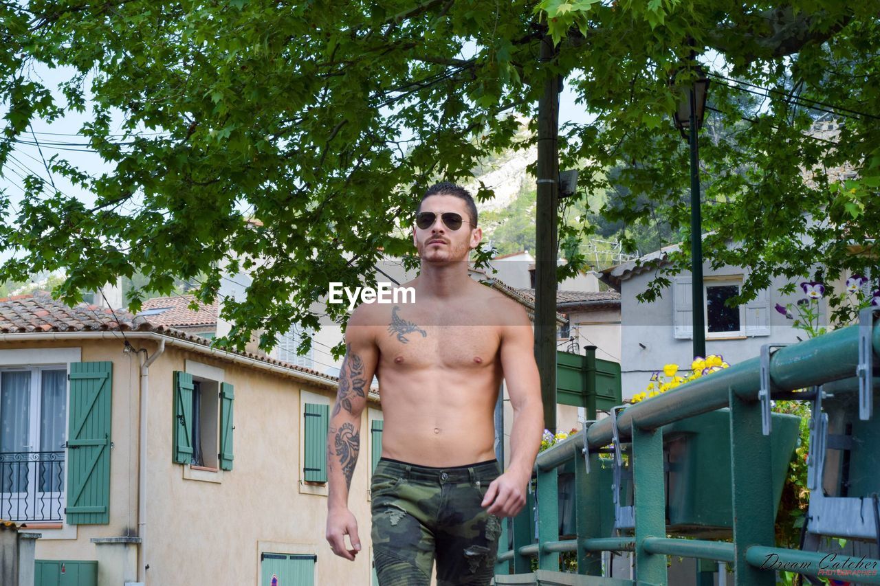 Shirtless tattooed young man walking in town