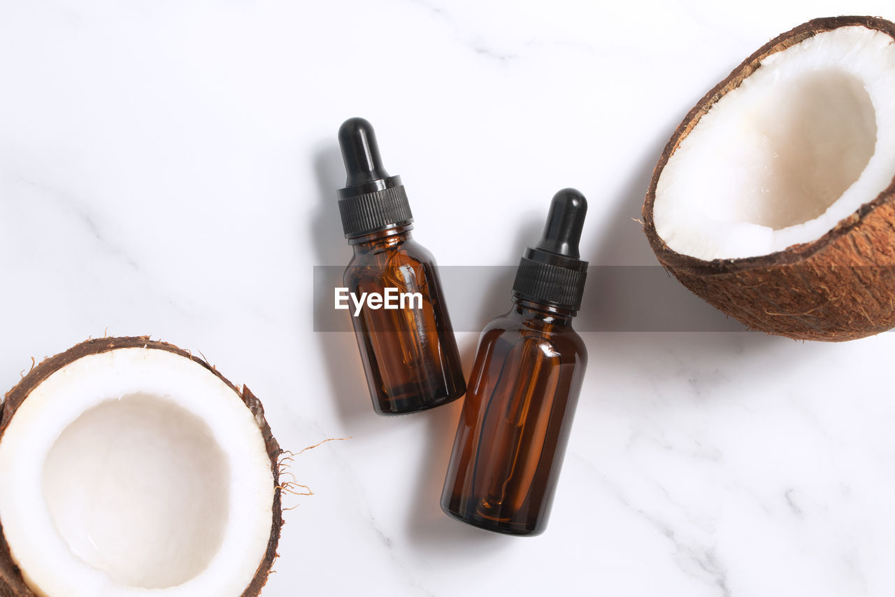 Bottles of coconut oil and fresh coconuts on marble background. coconut natural cosmetics.