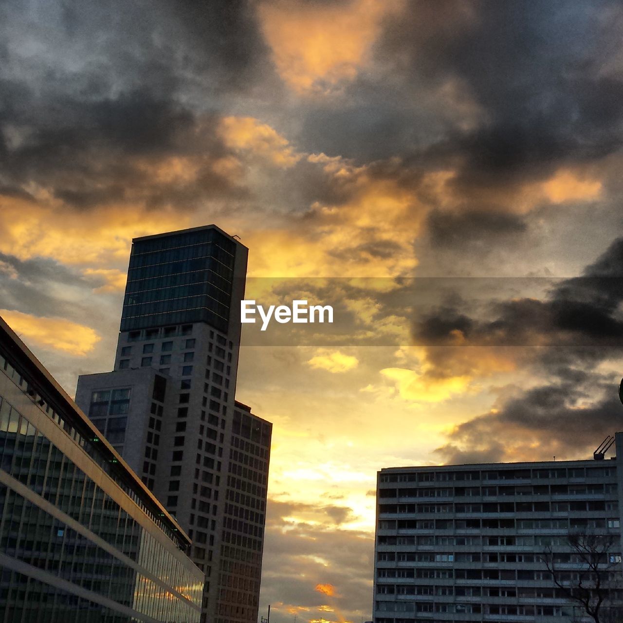 Low angle view of buildings against cloudy sky during sunset