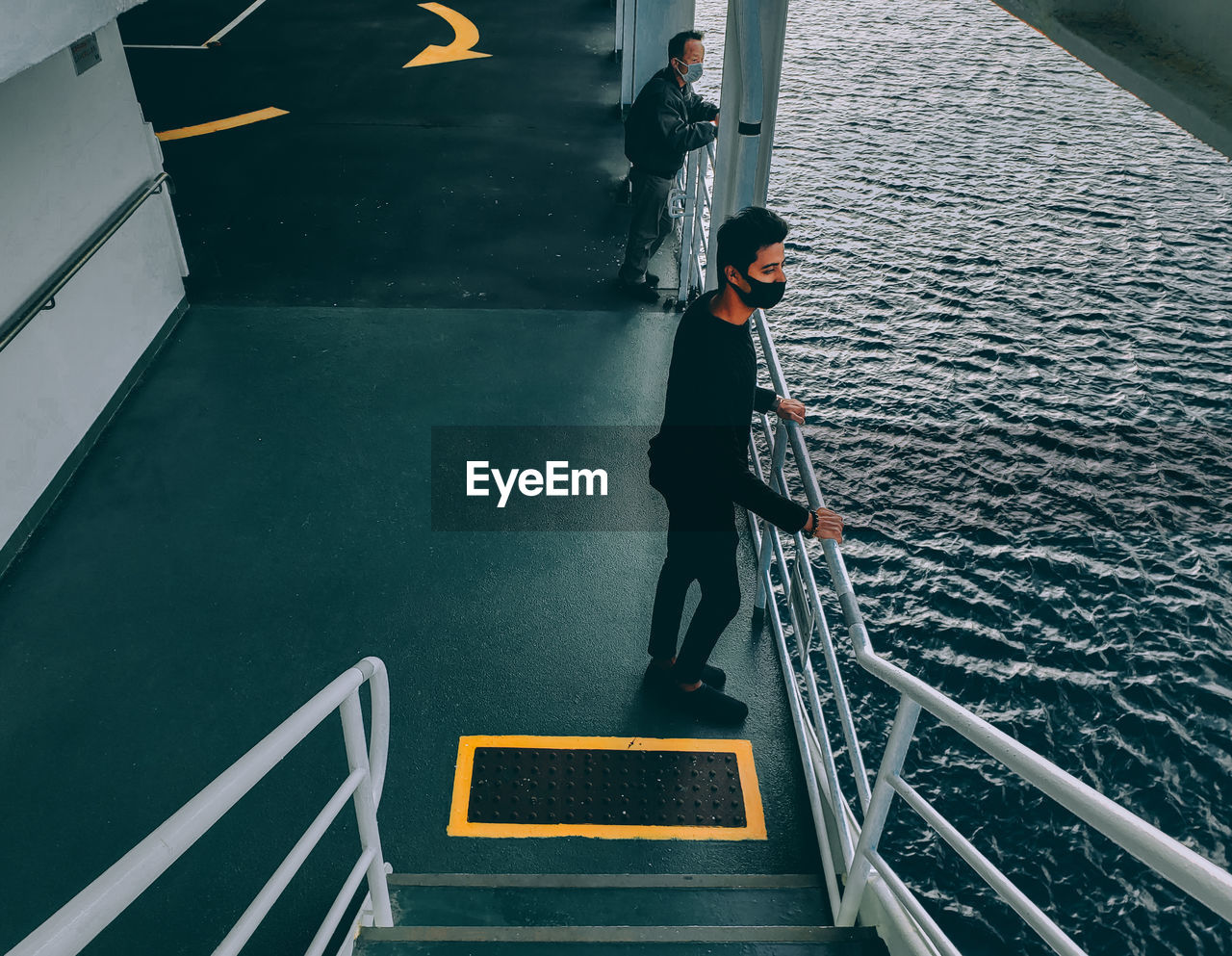 HIGH ANGLE VIEW OF MAN STANDING ON STAIRCASE AT WATER