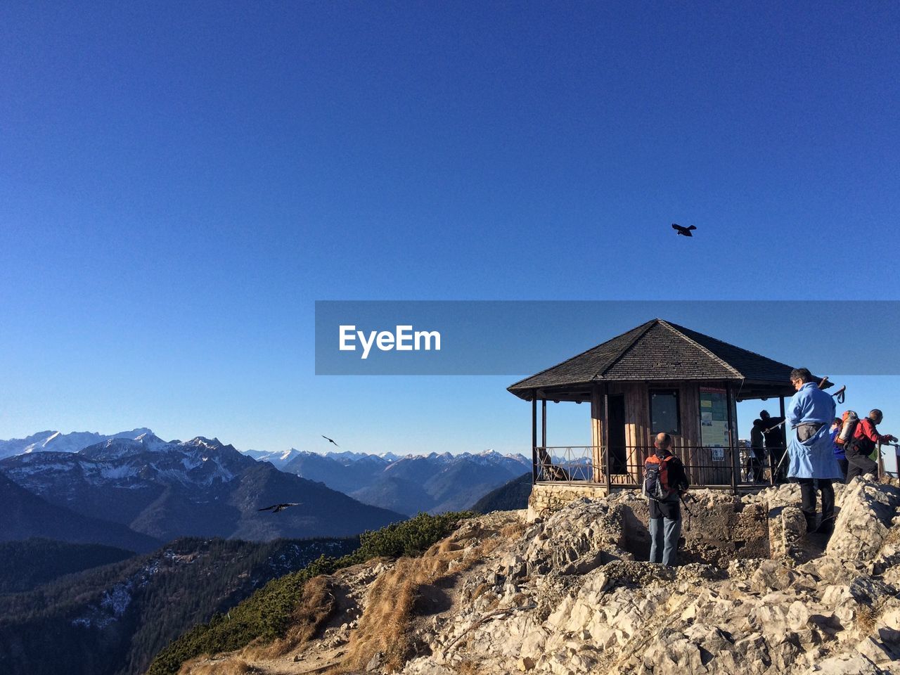 MAN STANDING ON MOUNTAIN AGAINST BLUE SKY