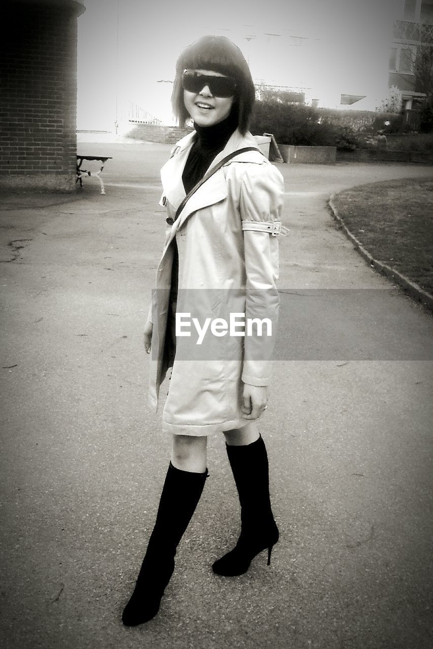 Portrait of smiling young woman standing on road